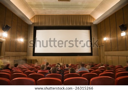 Old retro style cinema auditorium with line of red chairs, sitting visitors and silver screen. Ready for adding your own picture.