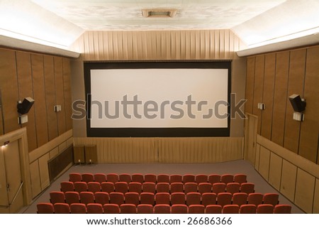 Old retro style cinema auditorium with line of red chairs and silver screen. Ready for adding your own picture.