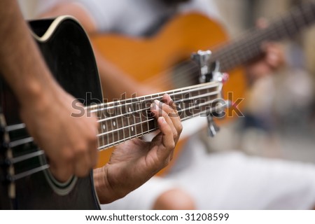 Street guitarists. Musicians are playing on guitars. Close-up of fingers pressing the strings of the instrument.