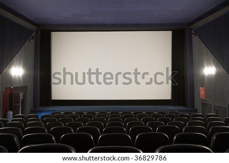 Empty cinema auditorium with line of chairs and stage with silver screen. Ready for adding your own picture.