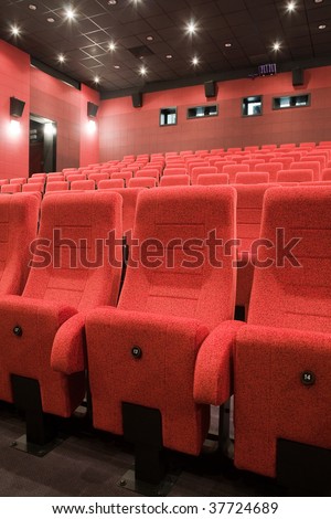 Interior of cinema auditorium with lines of red chairs.