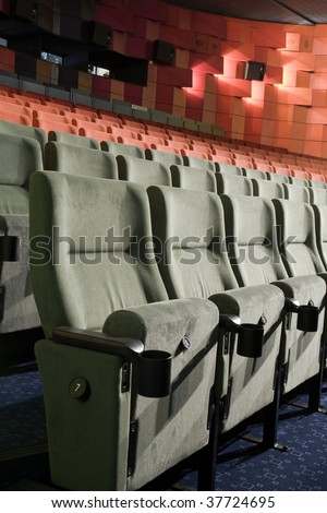 Green row # 7 of empty cinema auditorium with line of chairs.