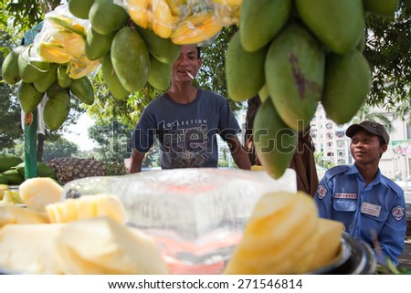 BURMA, RANGOON - FEBRUARY 12, 2011: Smoking man is selling fresh mango on street food market.