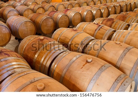 Selected wine varieties are aging in oak wine barrels  in a winery cellar.