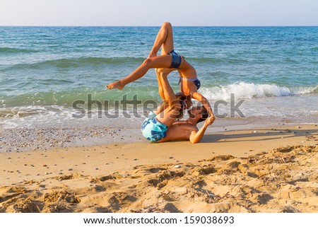 Summer afternoon at a sandy beach with the ocean in the background, a young couple practices a dance scene.