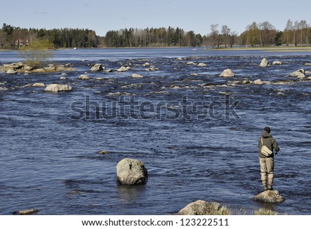 Fisherman catches a salmon river in spring. Farnebofjarden national park in Sweden