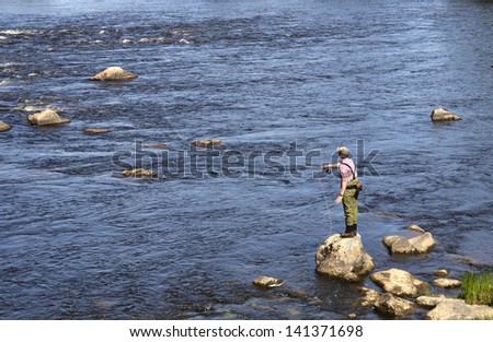 Fisherman casting in a salmon river at summer