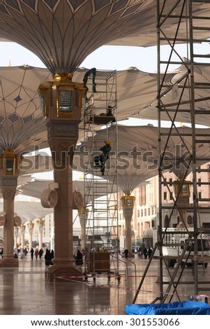 The employee was cleaning the giant umbrella.Taken on June 9.2015.in Prophet mosque Medina, Saudi Arabia