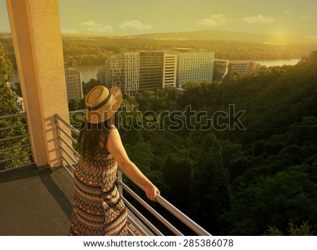 Woman from Behind Standing at Balcony Looking to Distance in Sunset