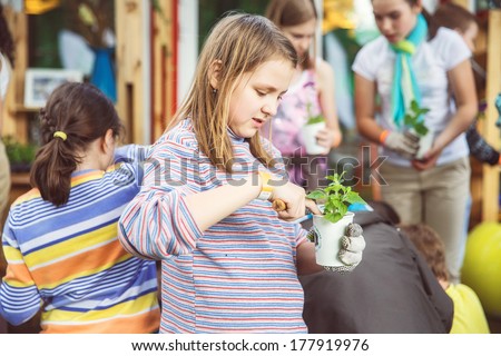 Moscow , Russia - june 1, 2013: Children plant flowers in paper cups and sign your name. Photo made at Moscow on  June 1st , 2013