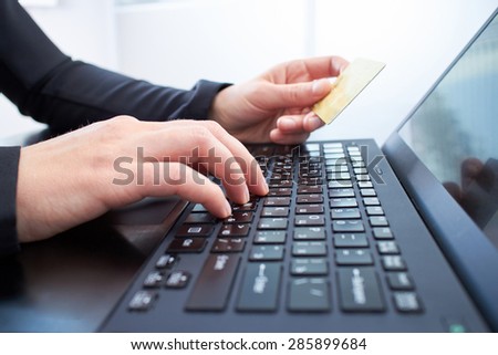 girl\'s hands on a black notebook keyboard and bank card