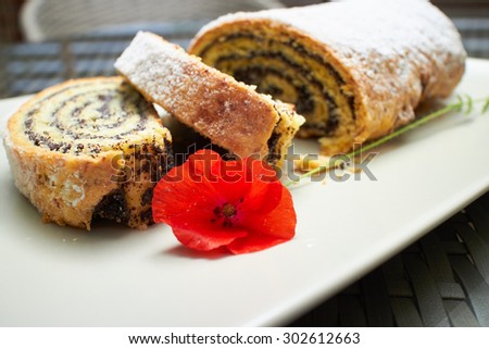 poppy seed roll cake dessert on a plate with a flower poppy in a street coffee