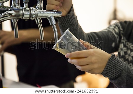 Woman drawing beer from tap in an inclined plastic cup