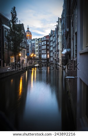 Romantic view of Amsterdam: canal in the Red District. Buildings and street lamps are reflected in the water