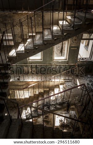 Concrete stairs illuminated with a picturesque light in an abandoned building in a sunny day. The light enters through some windows