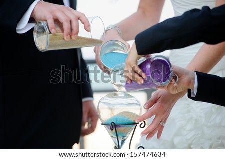 A wedding ceremony with a mixed family.  The groom, mother, and son perform a unity sand ceremony mixing each of their colors into one beautiful piece of art.