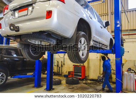SUV Car lifted in Service center for maintenance , Technician inspecting