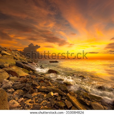 A beautiful digital manipulation scenery of sunset beach.Selective sharpening on the rock. Image have warmer white balance.Orange color cast.
