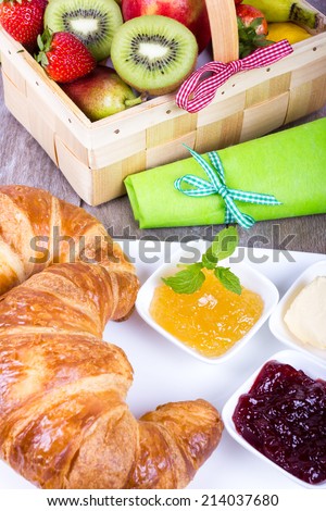 Breakfast with Croissant, butter, jam and coffee and fruit crate