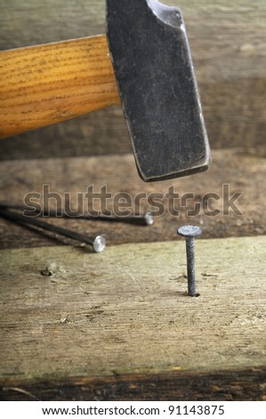 old hammer with a old nail against a wooden board