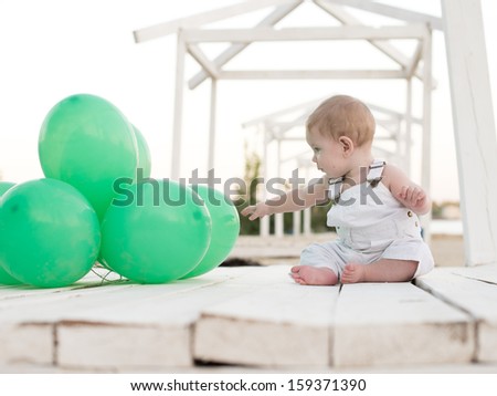 cute little boy in white with green balloons
