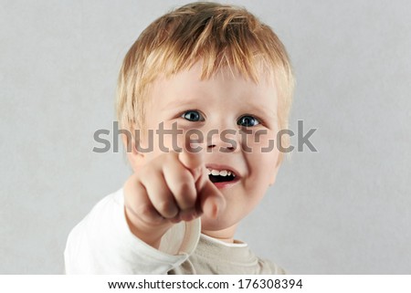 handsome happy blond boy points forward by finger. Positive human emotion facial expression feelings