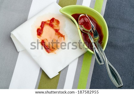 Big  spot of tomato ketchup  on a napkin near with plate