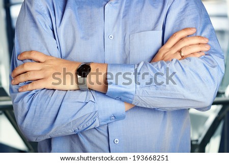businessman in  a blue shirt  standing  with arms crossed