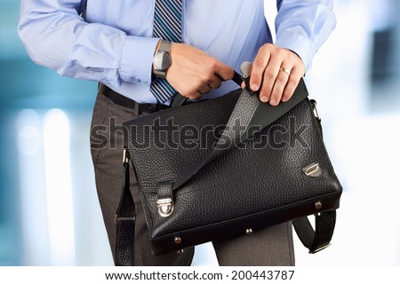 Businessman holding and opening  a  leather briefcase.