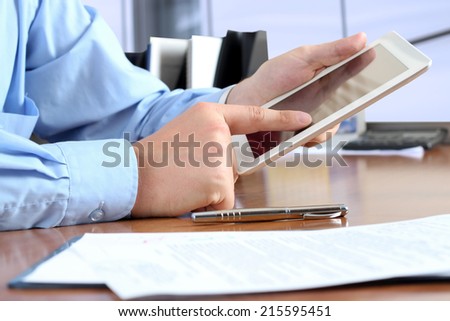 businessman  doing business, sitting at his desk in the office, analyzing  data in his digital tablet