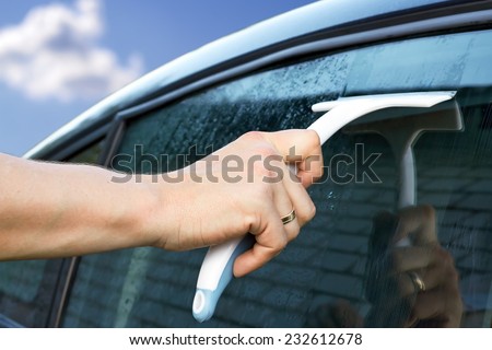 worker washing the car window with a scraper