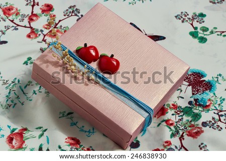 stylishly decorated  present box  with a red apples and a blue ribbon