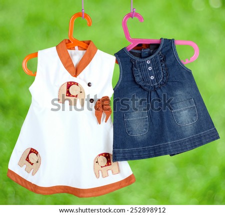 Fashion baby dresses hanging on a hanger on a green  background