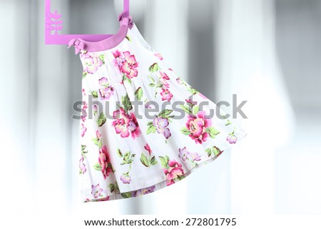 Fashion baby dress hanging on a hanger on a gray  background
