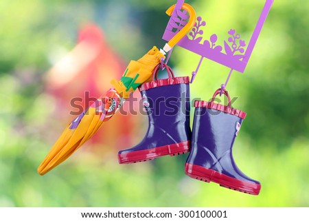 Pair of fashion rubber child boots  hanging with yellow umbrella