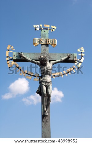 Sculpture of crucified Jesus Christ with Hebrew explanatory text, Prague, Czech Republic. Against blue sky.
