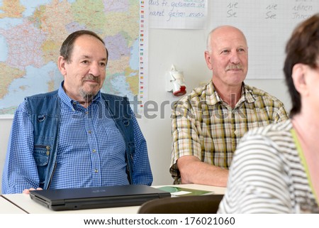 Two grown men sitting at a table in front of a world map.