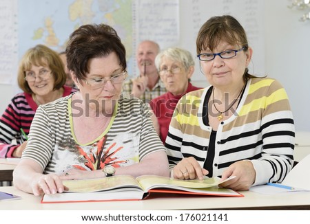 The two old women are sharing a book together.