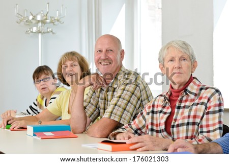 A group of elderly people sit at a table.