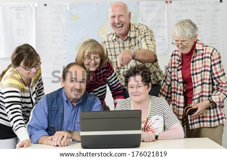 A group of elderly people behind a laptop.