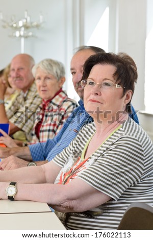 A group of elderly people are sitting in a classroom.