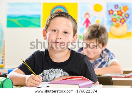 Two boys sitting in a class room waiting to write stuff down.