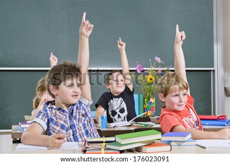 Four kids with their hands up to answer a question.