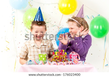 Two children with party hats being covered with confetti.