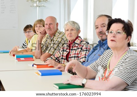 A group of elderly people sitting in a classroom.