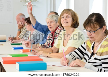 A group of elderly people sitting together at a table with books.