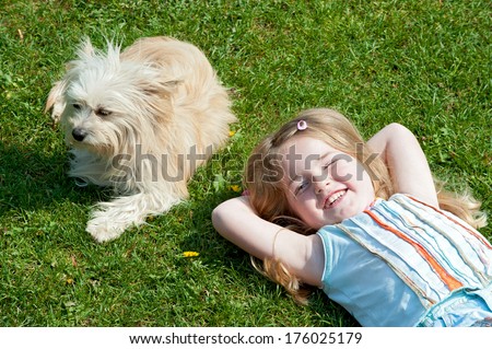 A girl laying in the sun with her dog.