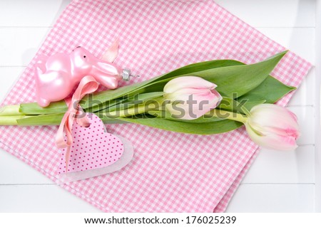 Two pink tulips sitting on a pink and white gingham cloth.