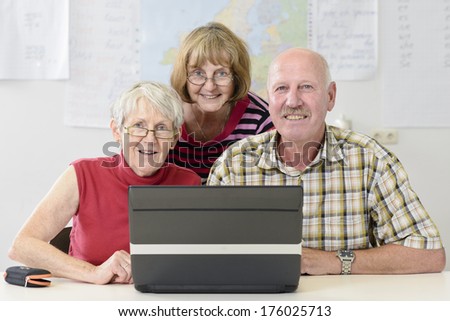 A photograph of three older people sitting in front of a computer.