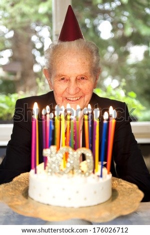 An elderly man looking at a cake topped with candles.